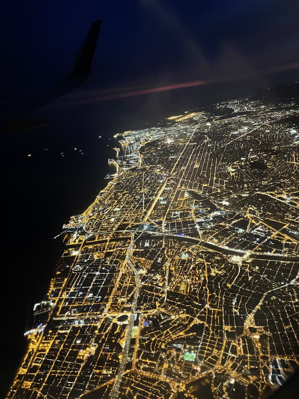 Vista aérea nocturna de una ciudad iluminada junto al mar